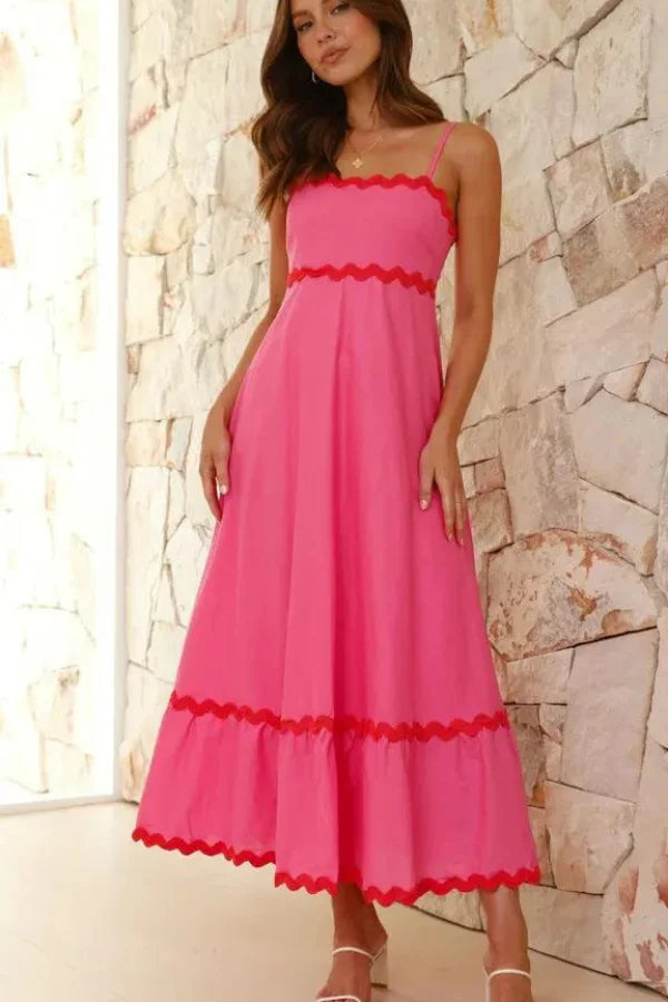 Model wearing the Kouvr Amillia pink scalloped maxi dress in front of a stone wall