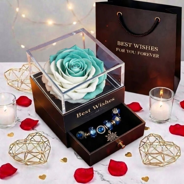 A fresh mint green and white preserved rose gift box sitting on a marble table with rose petals and candles.
