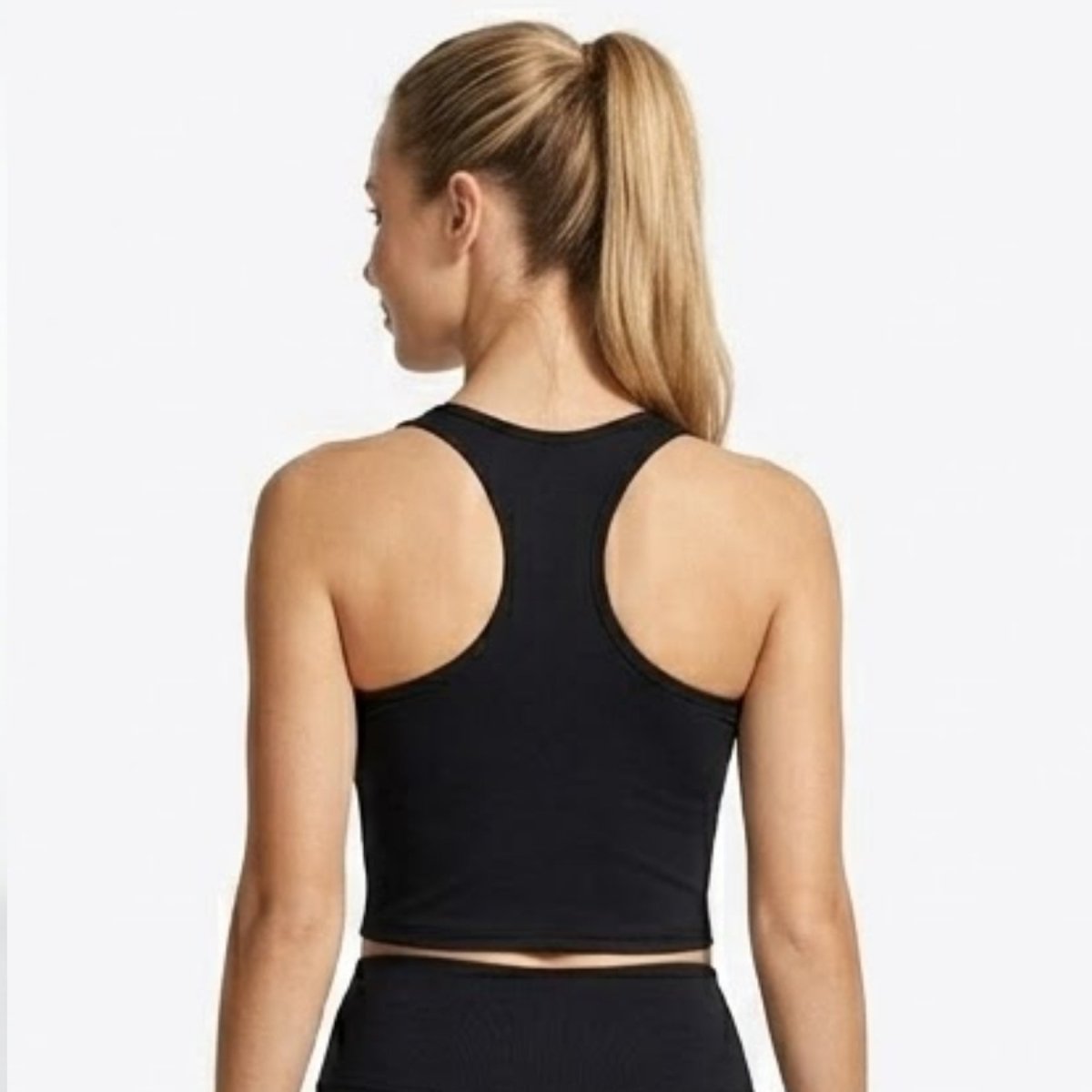 Back view of model wearing Kouvr black racerback sports bra showing supportive strap design and form-fitting silhouette.