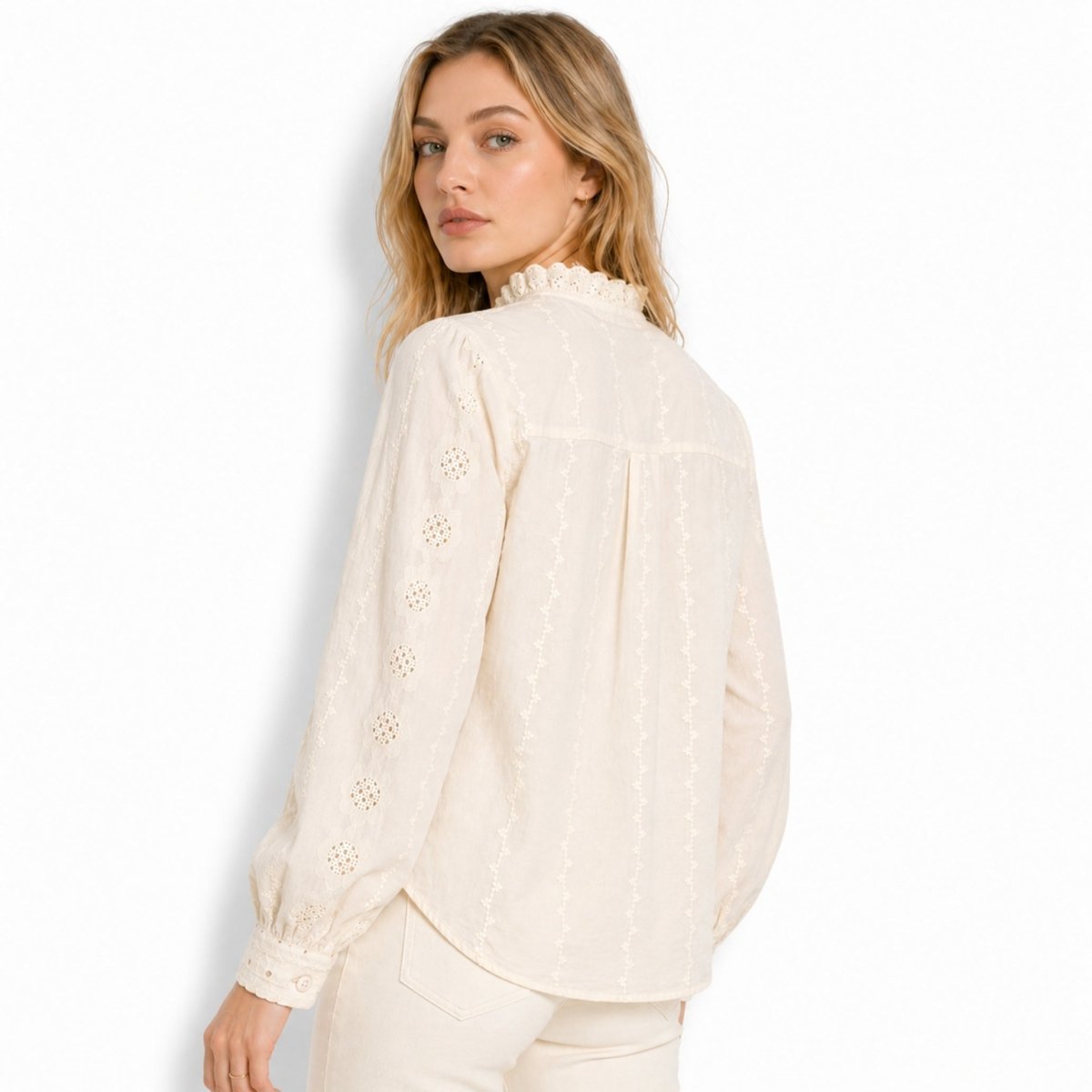 Back view of woman wearing an beige vintage-inspired blouse highlighting vertical embroidered floral accents and back yoke pleating.