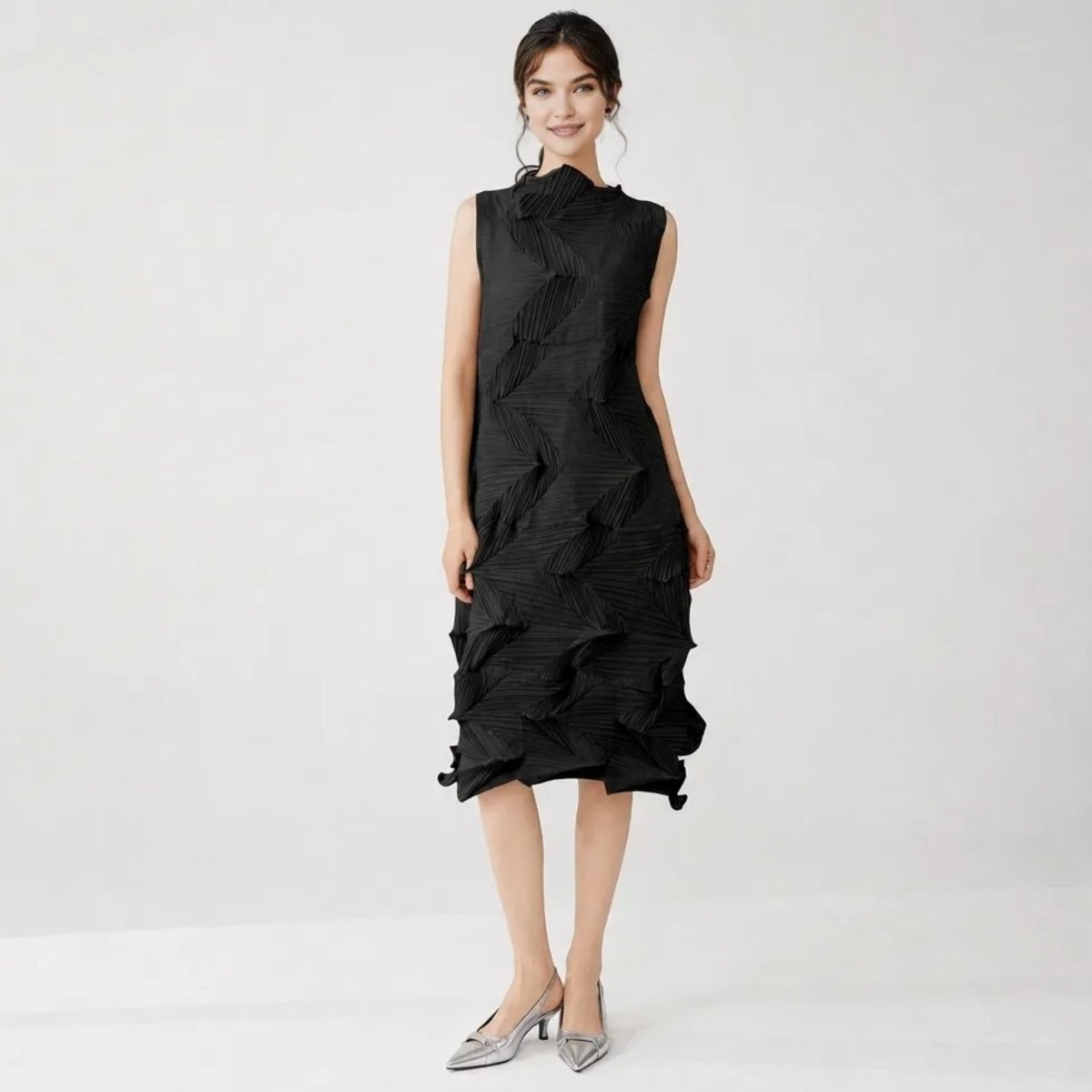Woman wearing a stylish black 3D architectural pleated midi dress with silver heels by Kouvr.