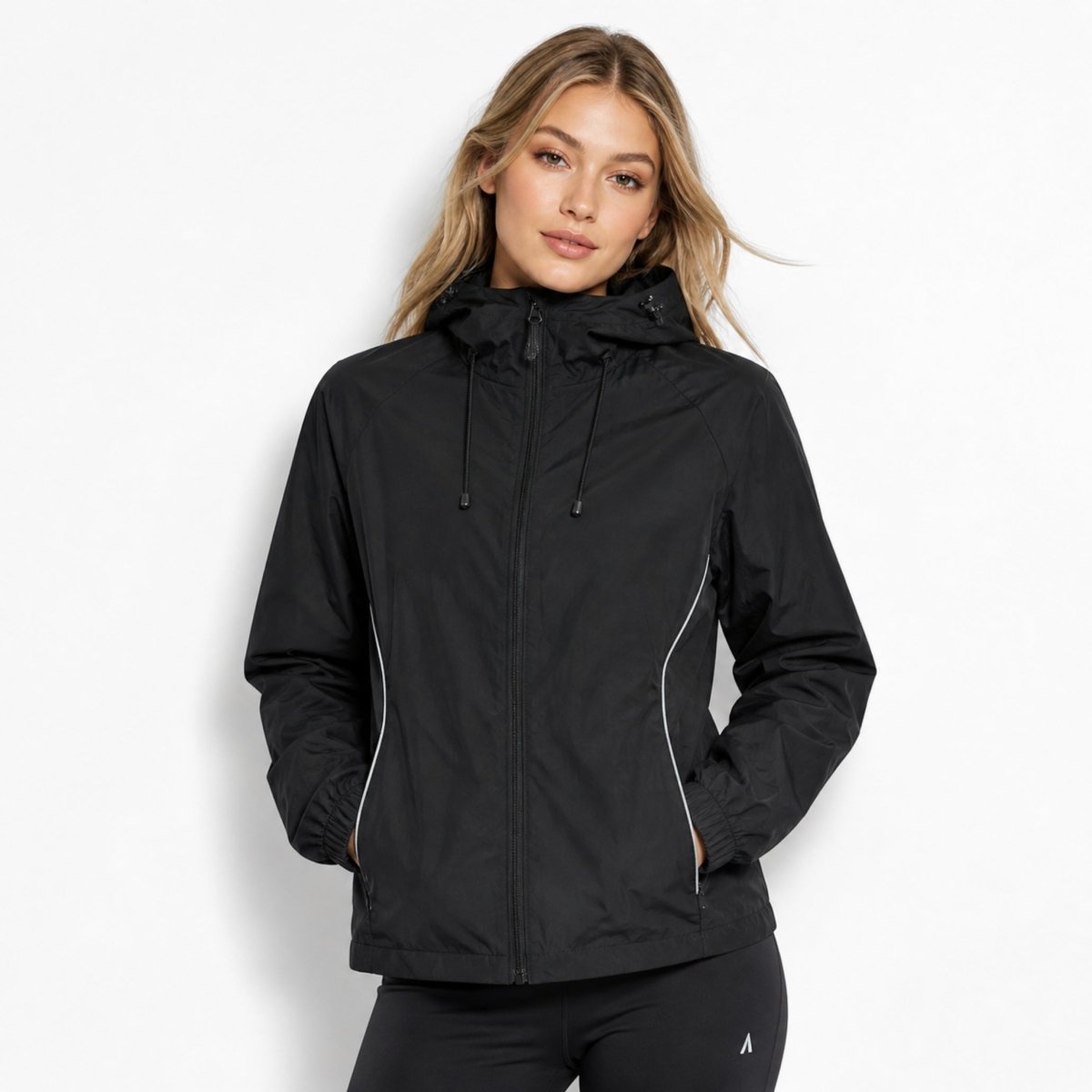 Woman wearing Kouvr black lightweight hooded windbreaker jacket with front zipper and reflective trim.