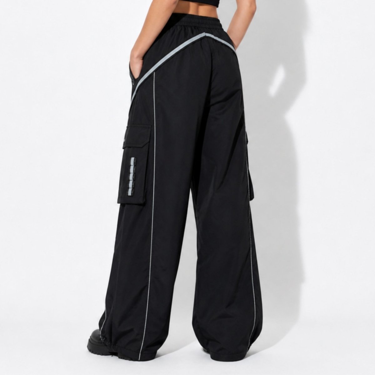 Detail view of adjustable toggle hem and side utility pockets on black techwear streetwear pants