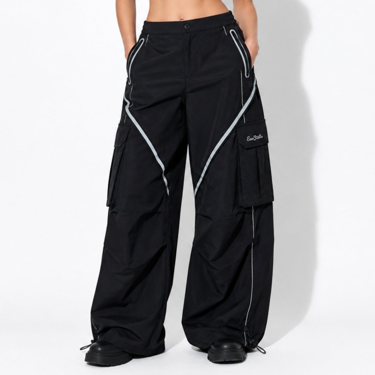 Woman wearing Kouvr black wide leg parachute cargo pants with contrast geometric piping front view