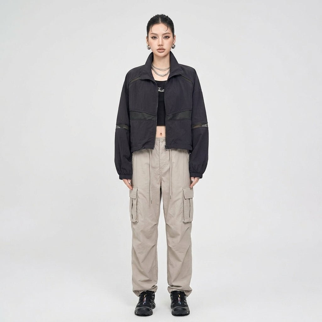 Fashion model wearing Kouvr black techwear zip up jacket styled with beige utility cargo pants