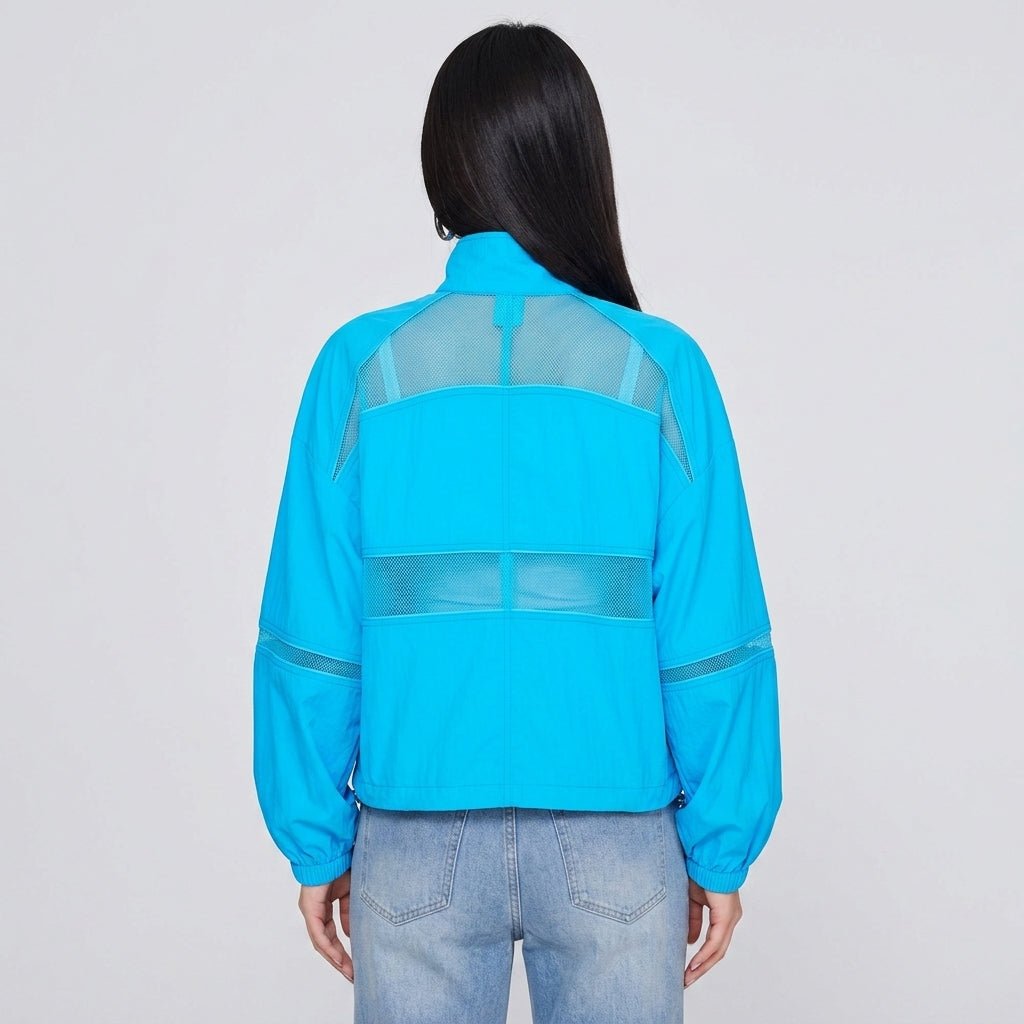Back view of woman wearing Kouvr bright blue lightweight athleisure jacket showcasing horizontal mesh ventilation detailing.