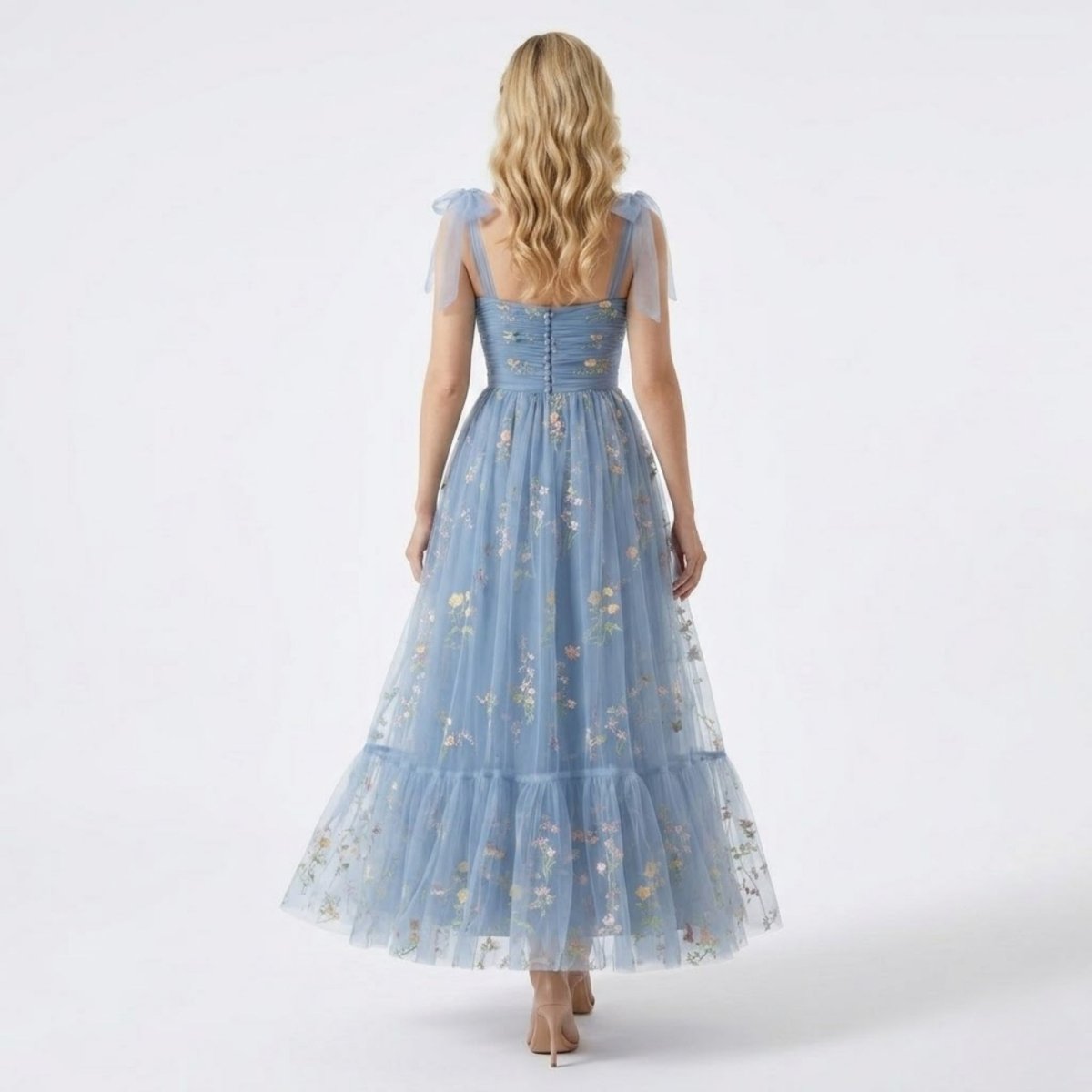 Back view of the Kouvr blue floral tulle gown highlighting elegant decorative covered buttons and sheer tulle tie shoulder bows.