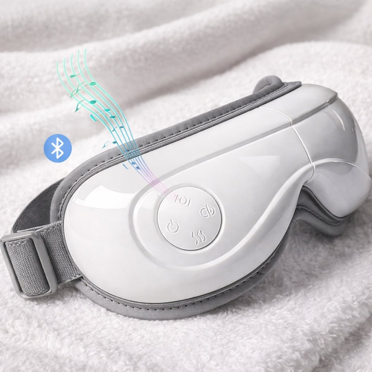 Sleek white KVOUR eye massager resting on a plush white towel showcasing Bluetooth connectivity for an immersive music experience.