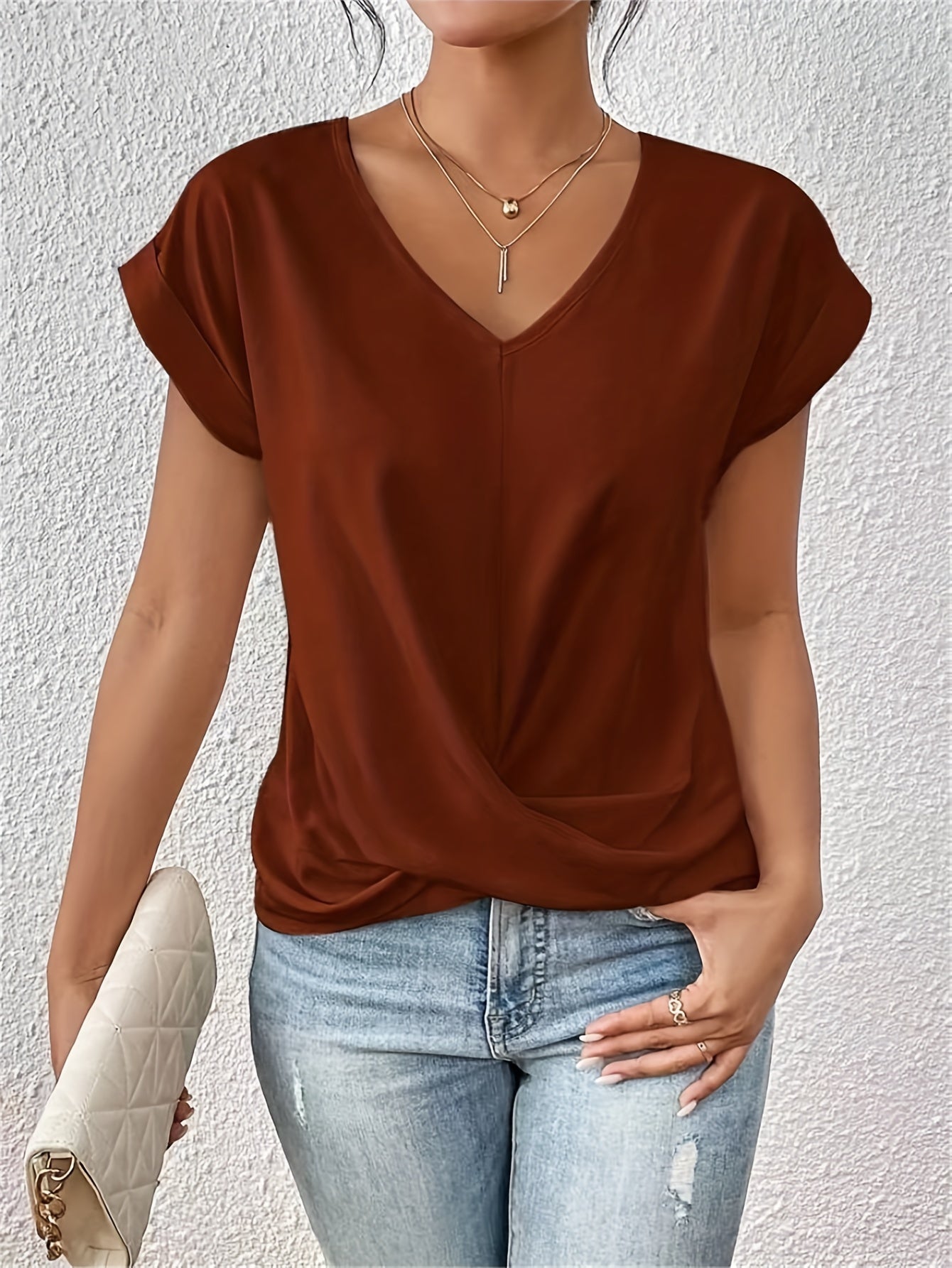Woman wearing a brown top and blue jeans against a light gray background
