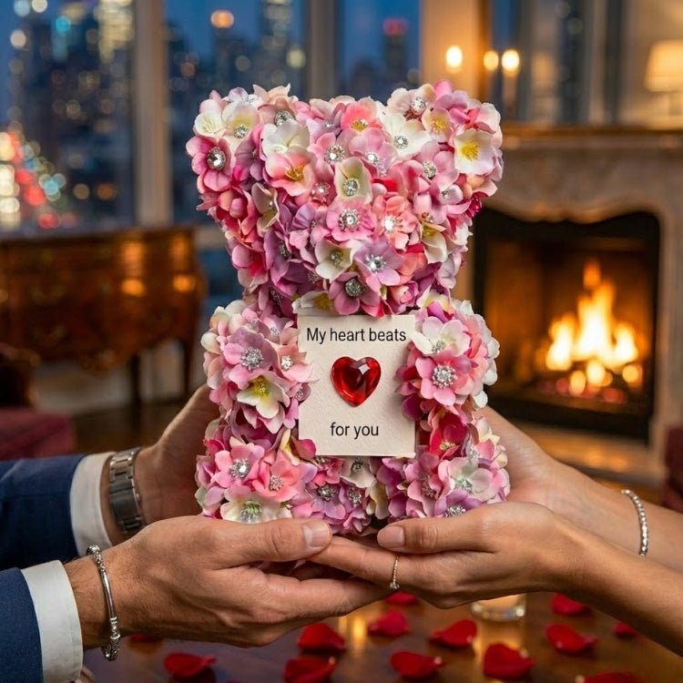 A close-up of a man's hands giving the pink floral Kouvr bear with a 'My heart beats for you' card to a woman.