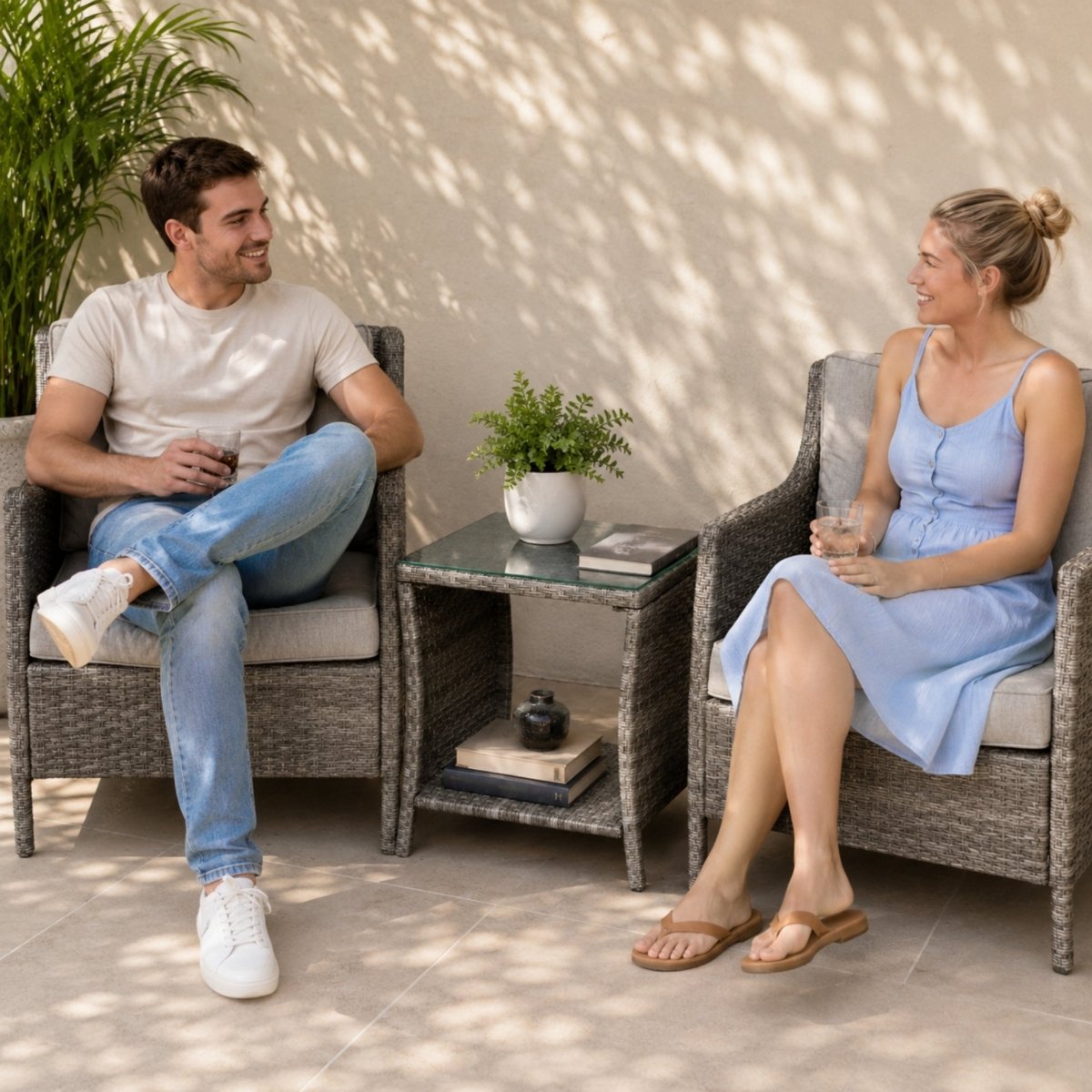 Couple relaxing on a patio with drinks resting on a modern grey wicker outdoor side table with a glass top.