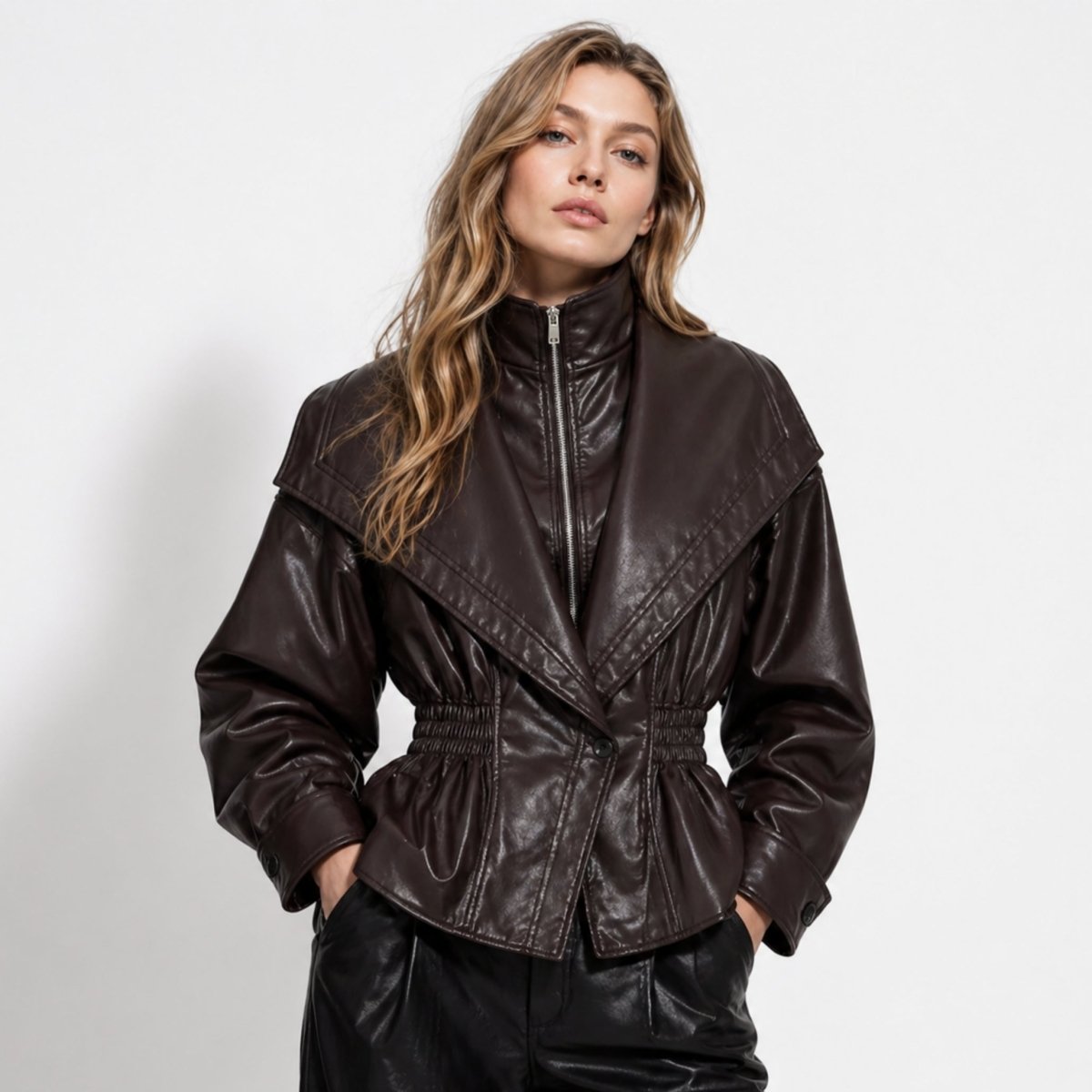 Woman wearing a dark brown faux leather peplum jacket with oversized collar and smocked waist, front view.