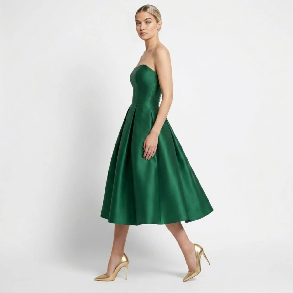 Side profile of a blonde fashion model walking in a formal green fit and flare cocktail dress paired with gold stiletto heels.