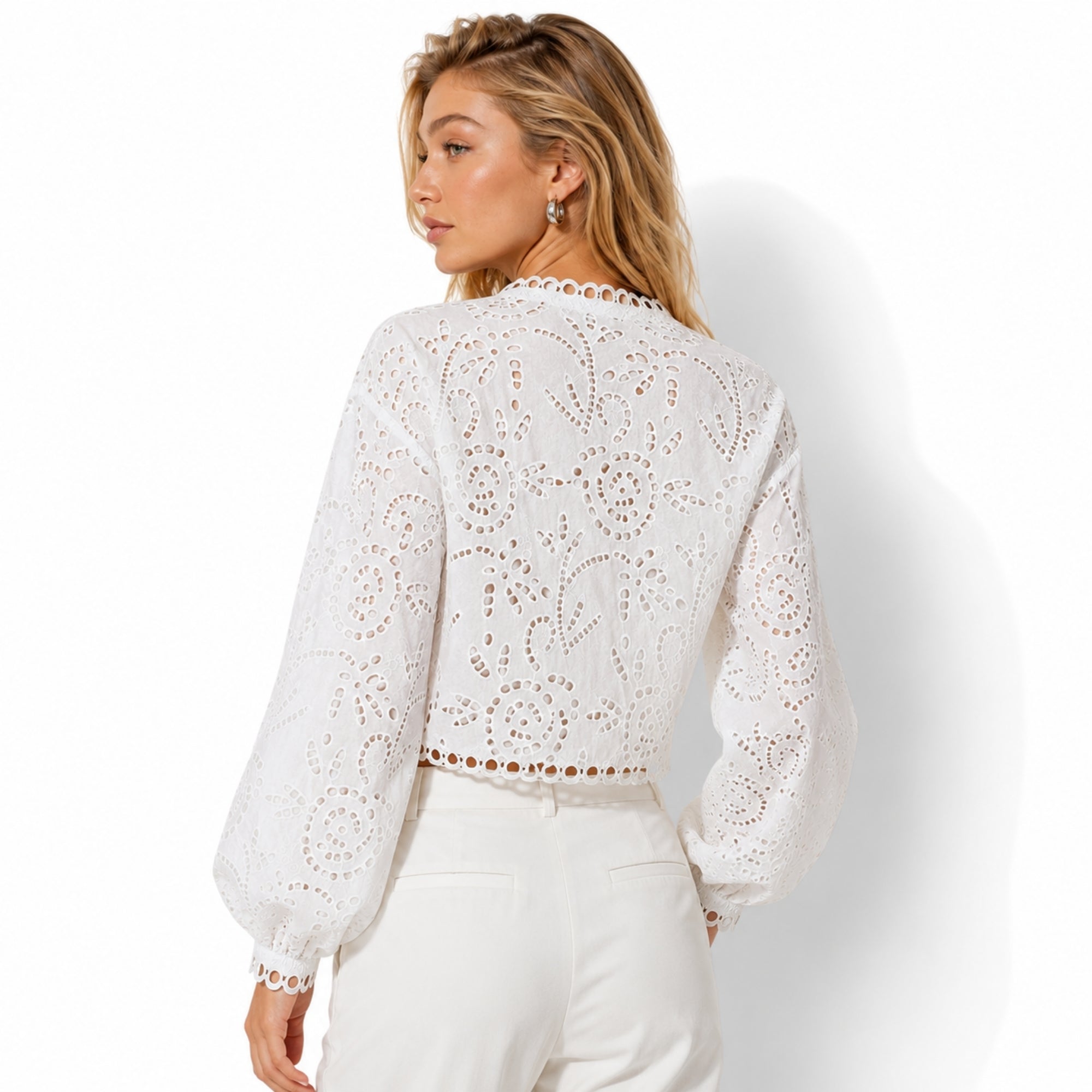 Back view of the Kouvr scalloped edge white eyelet top highlighting intricate floral lace patterns and cropped hemline.