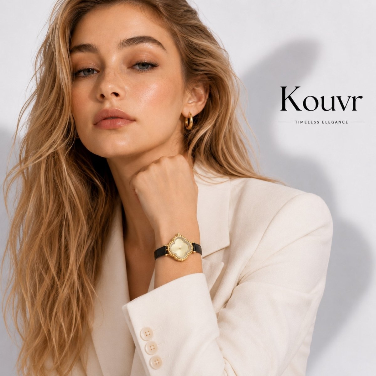 Elegant blonde woman modeling the Kouvr gold clover vintage watch styled with a tailored white blazer.