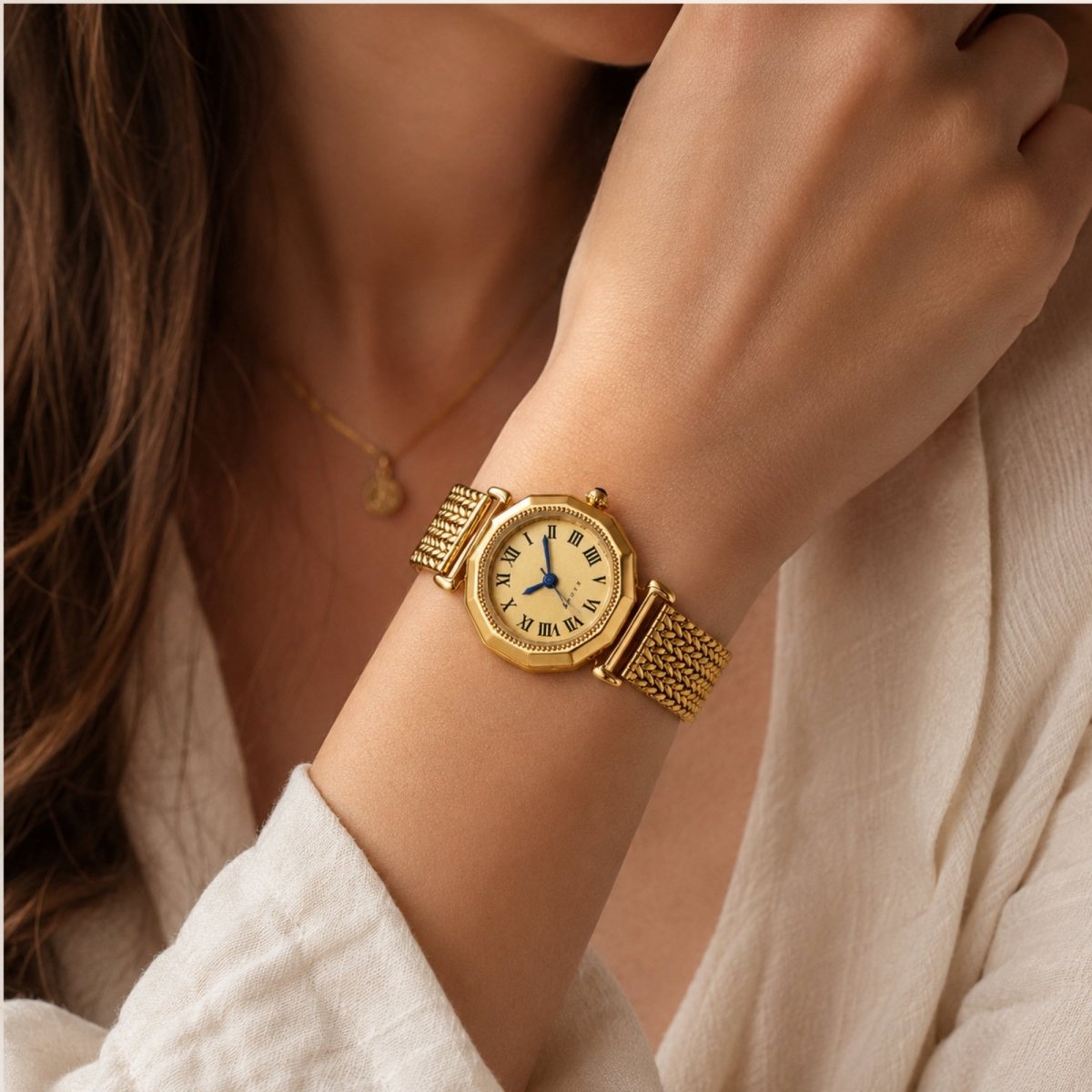 Elegant woman wearing a vintage gold octagonal watch with an adjustable mesh strap paired with a linen shirt