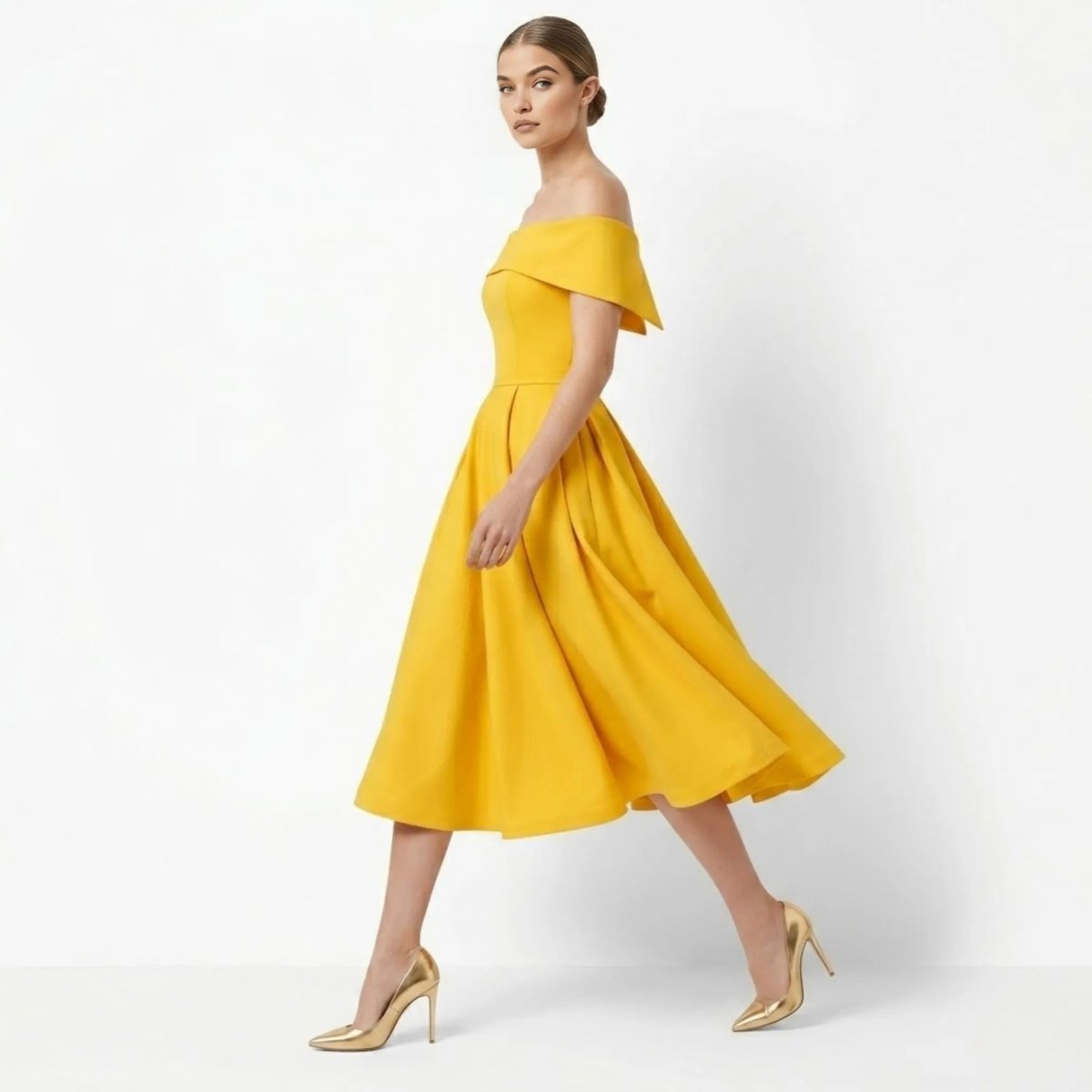 Side profile of woman walking in flowing gold fit and flare cocktail dress with metallic heels
