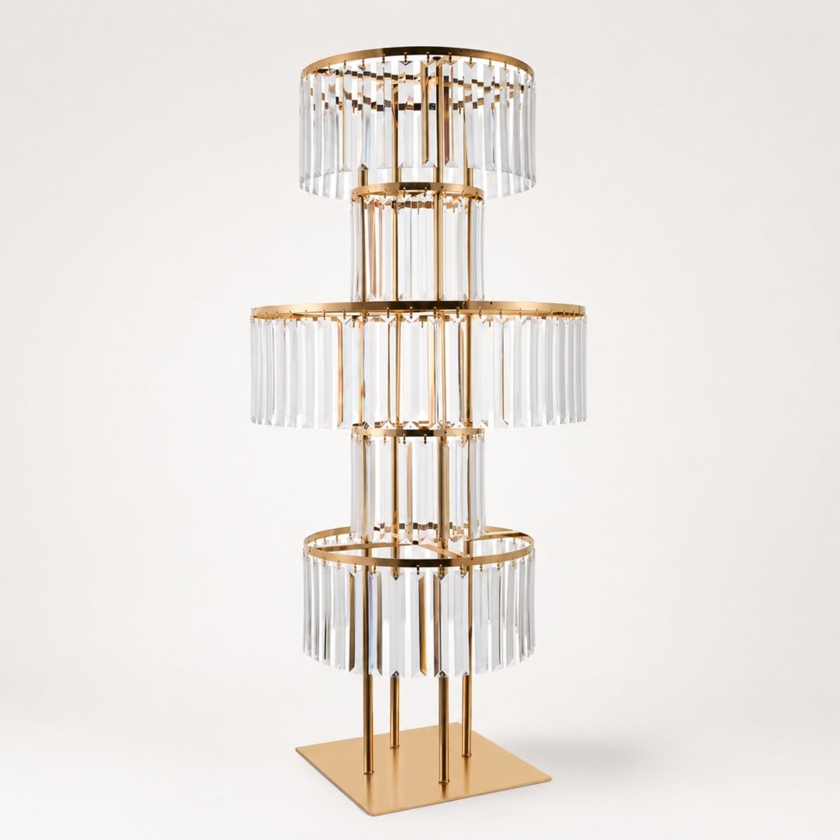 Studio product shot of an empty gold three-tier crystal acrylic event centerpiece stand on a square base.