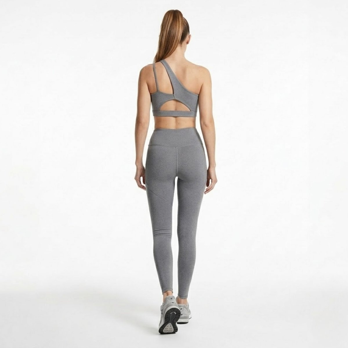 Back view of Kouvr grey workout set showcasing the sports bra shoulder strap cutout and contoured lifting glute seams on the leggings.