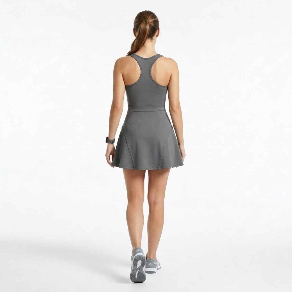 Back view of a grey racerback sports dress showing contoured structural seams and flared skater skirt
