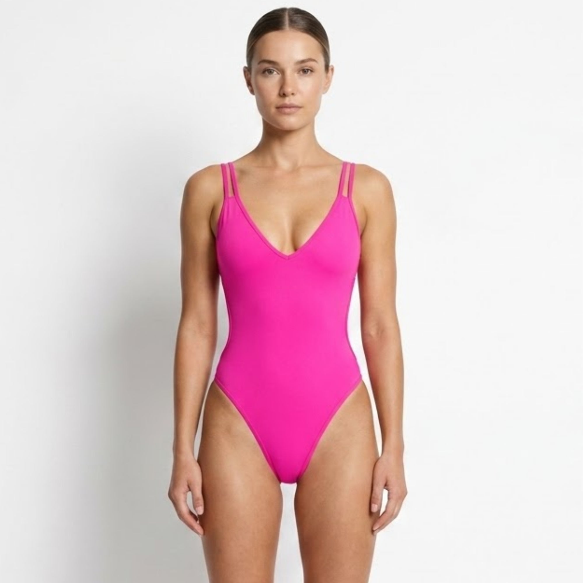 Model wearing the striking hot pink luxury one piece swimsuit with a deep plunge neckline for elegant resort wear.
