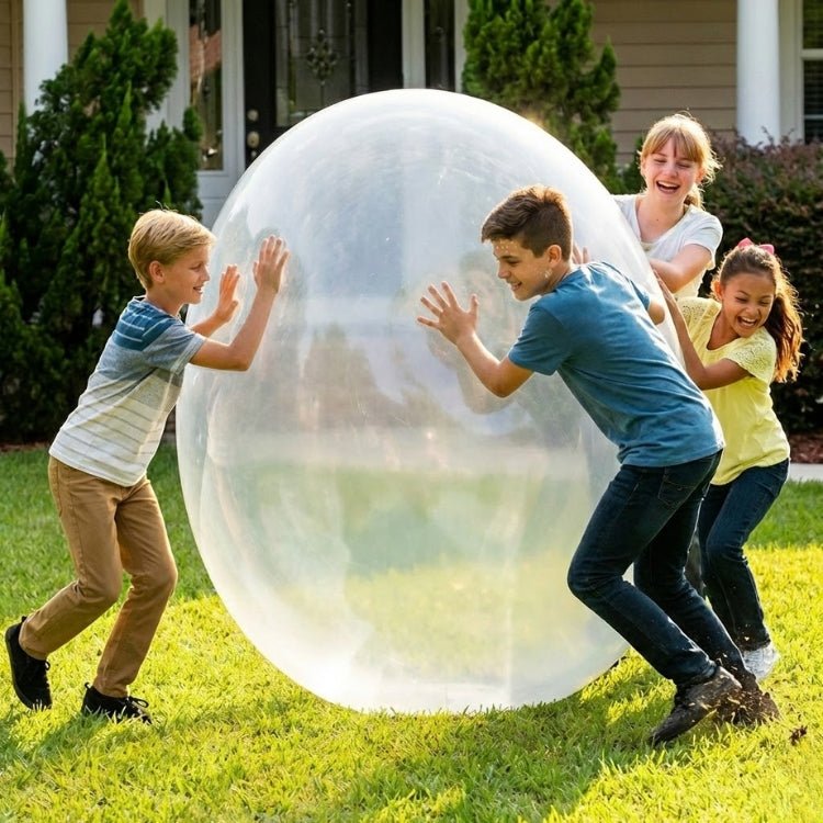 A group of four happy children playing together, pushing a massive clear inflatable bubble ball in a grassy yard.