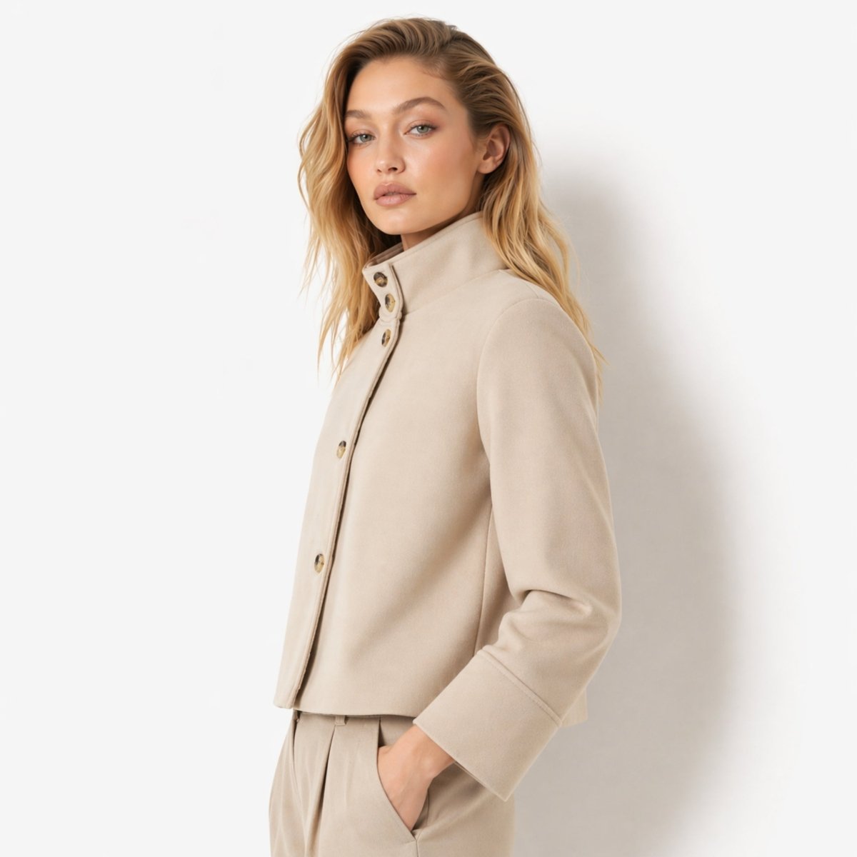 Side view of the Kouvr khaki neutral short coat showing wide cuffed sleeves and boxy fit.