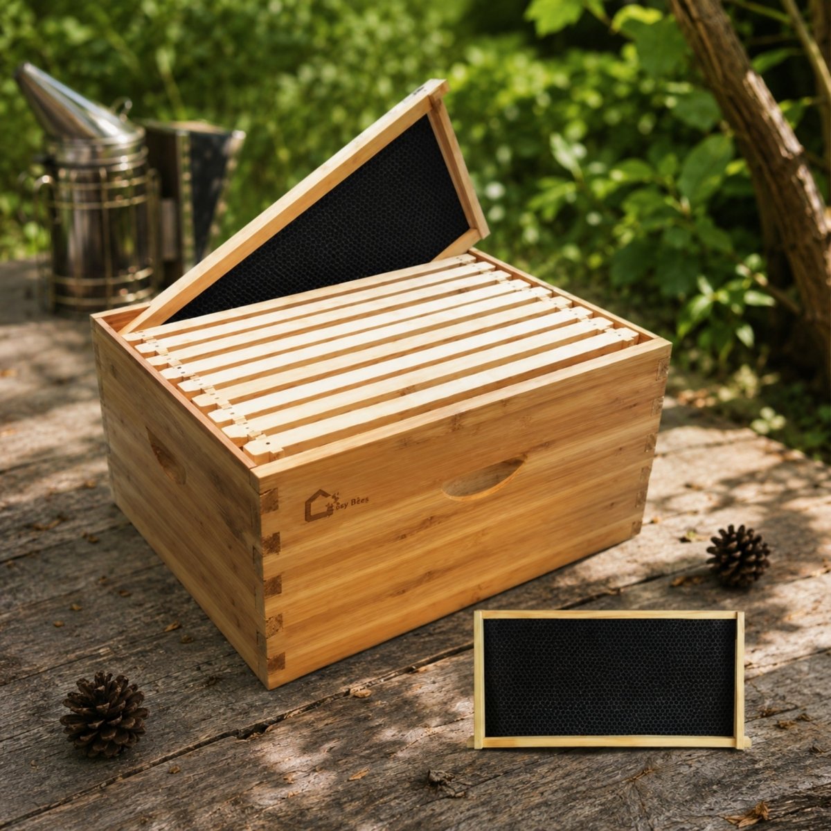 Premium Kouvr 10-frame cedar deep brood beehive box resting on a wooden table outdoors with an open lid exposing black foundation frames and a beekeeping smoker in the background.
