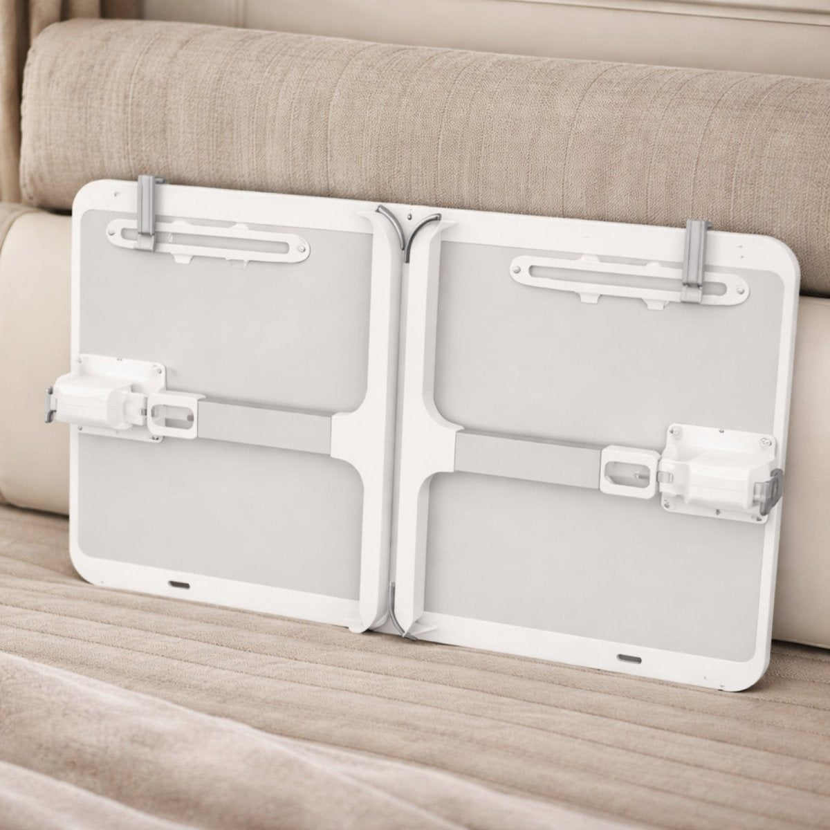 The Kouvr lap desk in its fully folded, compact state, leaning against a sofa to demonstrate its slim profile for easy storage.