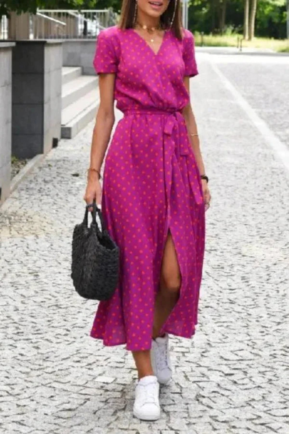 Woman walking in the Kouvr Aleia magenta and orange polka dot midi wrap dress with white sneakers