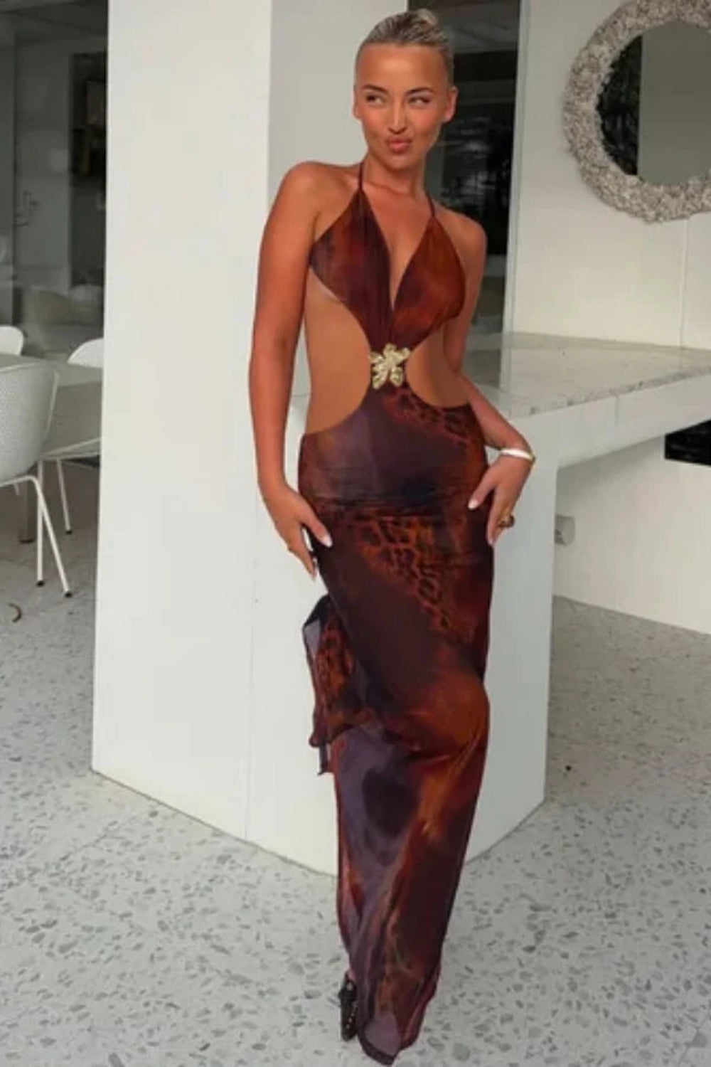 Model wearing the Kouvr Alexa brown leopard print cutout maxi dress with a halter neck and gold butterfly detail