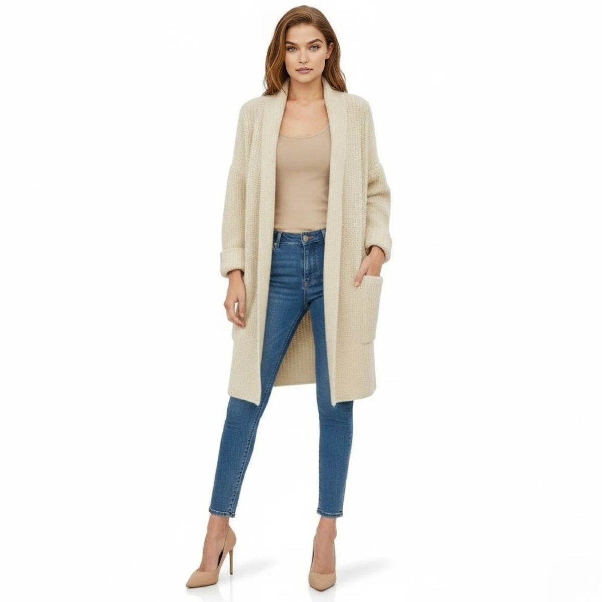 Model wearing the Kouvr Analyn long knit duster cardigan in ivory, styled with blue skinny jeans and nude high heels, shown from the front.