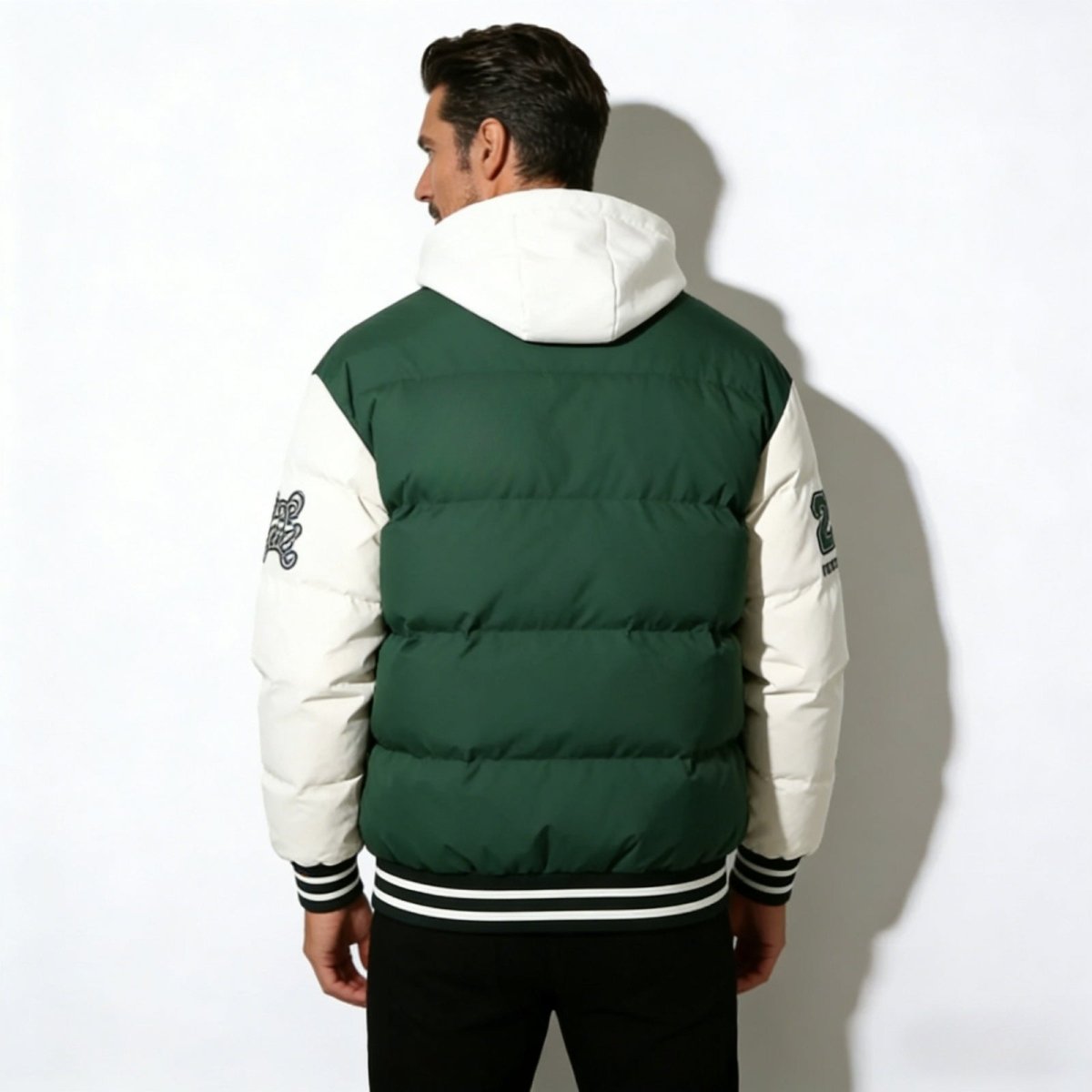 Back view of the Kouvr Angelo Hooded Puffer Varsity Jacket, displaying the horizontal quilting on the green body and patches on both sleeves.
