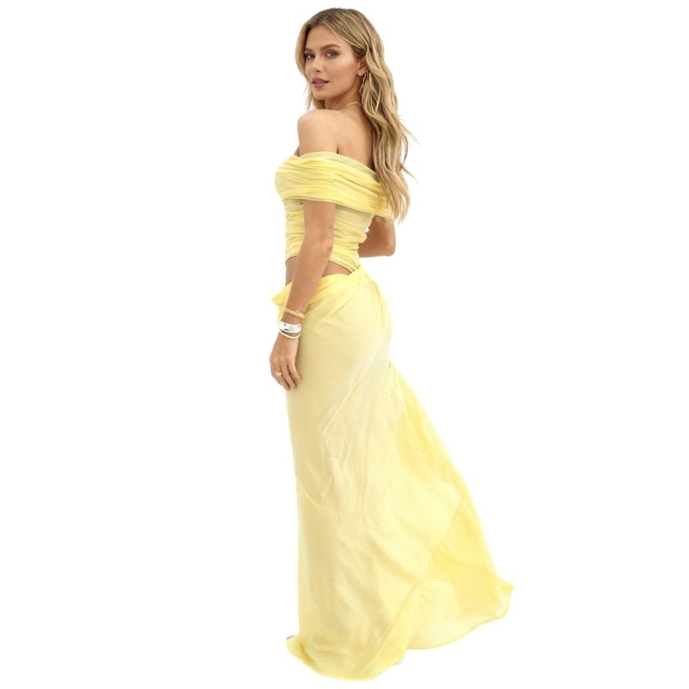 Model wearing the Kouvr Anita Gown in Lemon Chiffon, a yellow off-the-shoulder maxi dress with a side waist cutout
