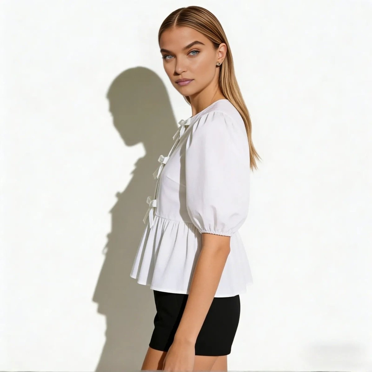 Side view of a model in the Kouvr Anne white puff sleeve blouse showing the peplum hem and sleeve volume.