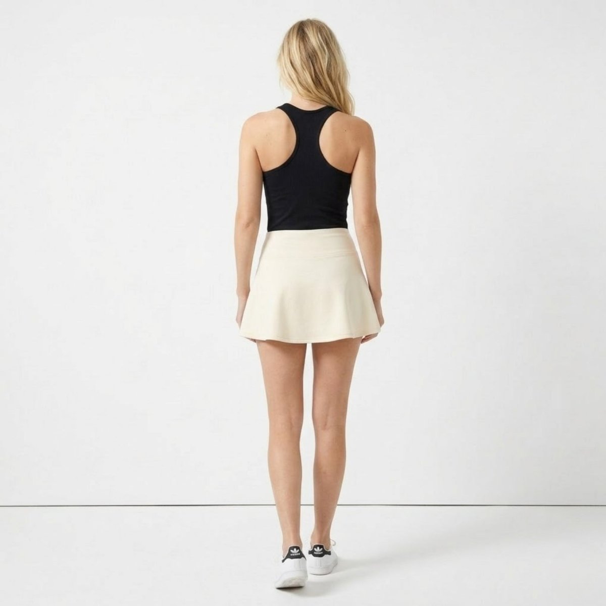 Back view of Kouvr apricot athletic outfit showing fitted ribbed square neck tank and flared mini skirt
