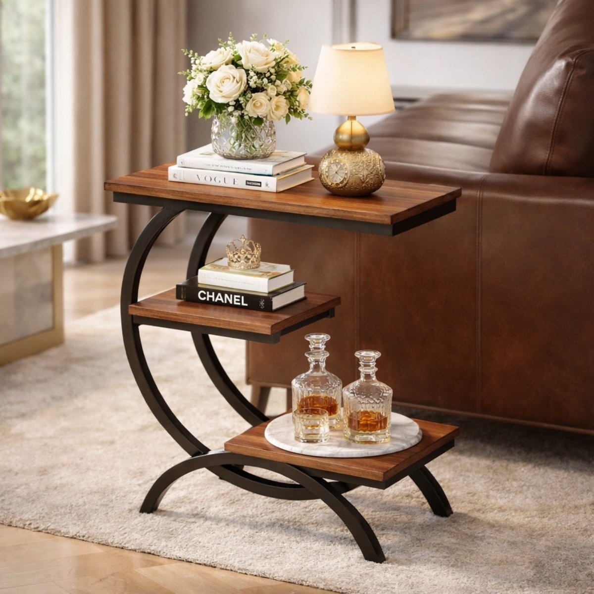 Detailed shot of the Kouvr Arcadian 3-tier accent table placed beside a leather sofa, showing its curved black metal frame and walnut wood shelves.