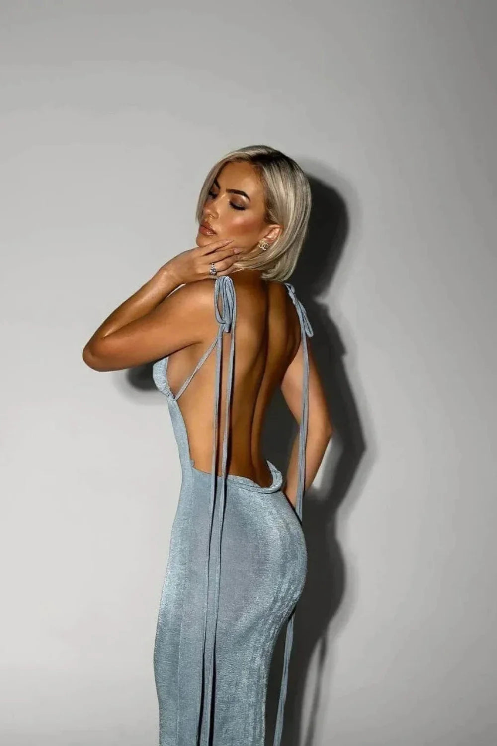 Model wearing Kouvr Ari light blue backless satin midi dress with tie shoulders against a white background