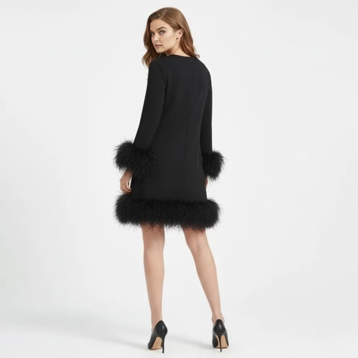 Model from behind wearing the Arica long sleeve black mini dress with voluminous feather trim on the cuffs and hem by Kouvr.