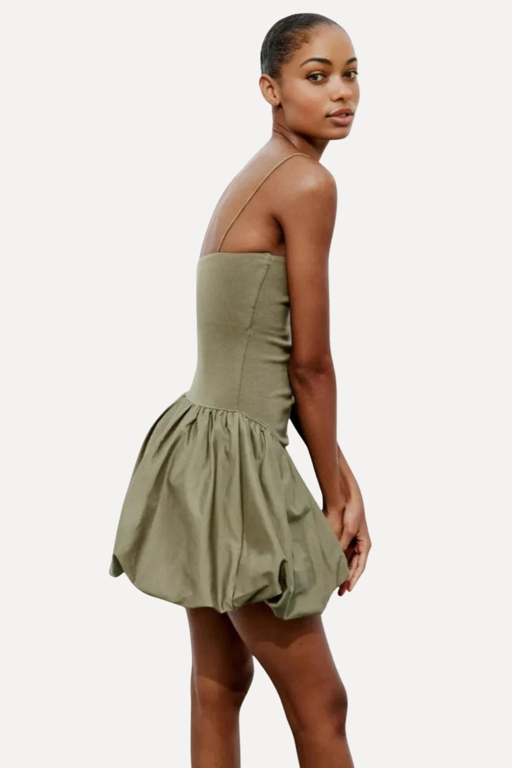 Model from the back wearing the Kouvr Aubrey olive green drop waist mini dress with a sculptural bubble skirt