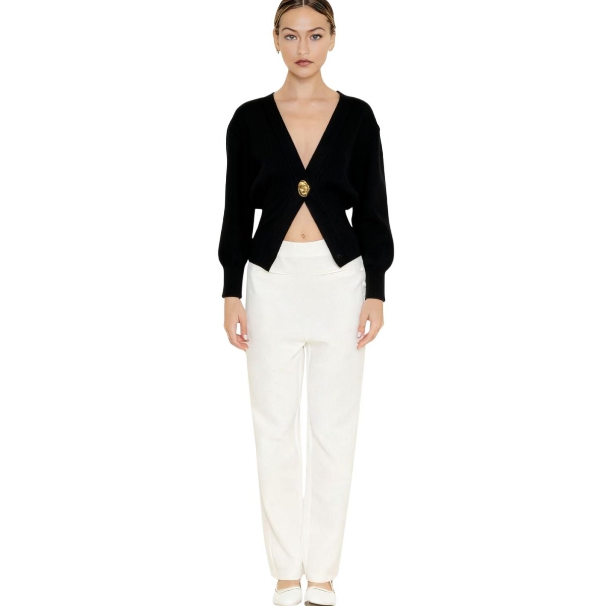 Model wearing Kouvr Avaline black ribbed knit cardigan with a statement gold clasp, paired with white trousers.