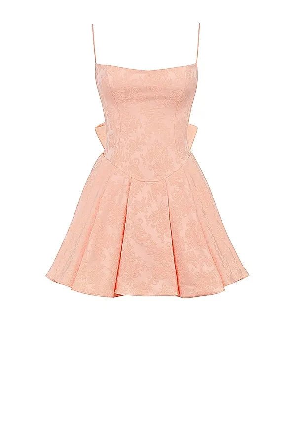 Model wearing Kouvr Ayliah peach jacquard mini dress with large bow detail at the back