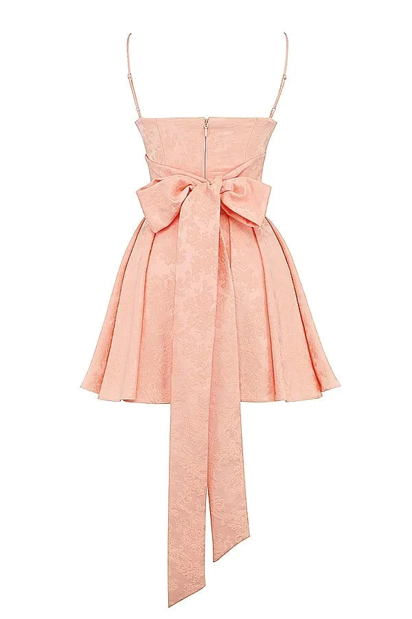 Model wearing Kouvr Ayliah peach jacquard mini dress with large bow detail at the back