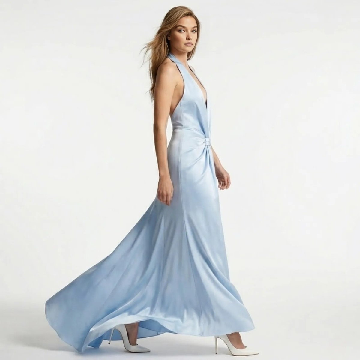 Side view of a model walking in the light blue Beverly satin halter gown, showing the dress's flow and open-back design.