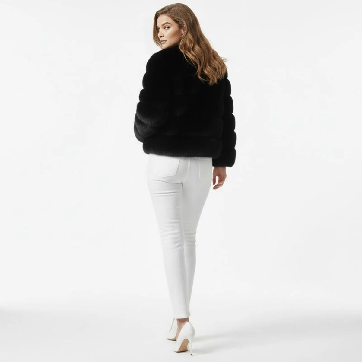 Back view of a model walking away wearing the Kouvr short black faux fur coat.