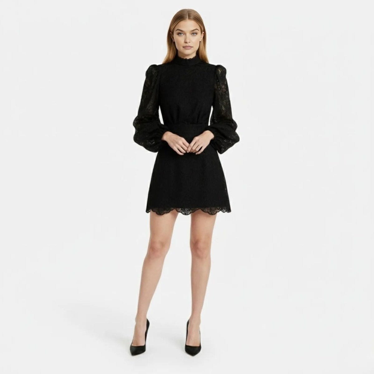 Full-length front view of a model wearing a black long-sleeve lace mini dress with a high neck and bishop sleeves, paired with black heels.