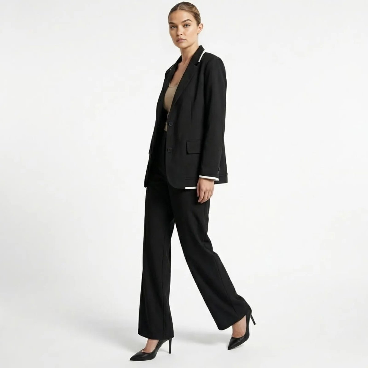Side profile of a model walking in the Kouvr black blazer and wide-leg trousers set, showing the suit's fluid movement and tailored fit.