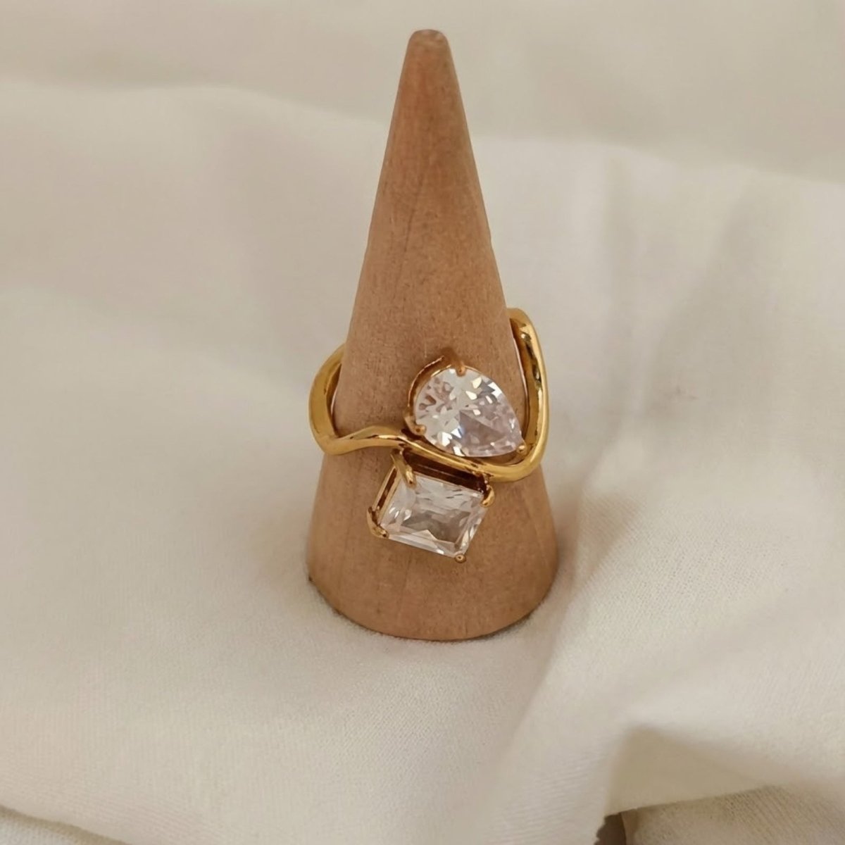 The Kouvr Blanca Toi et Moi ring displayed on a wooden cone, highlighting its unique wrap-around shape and brilliant stones.