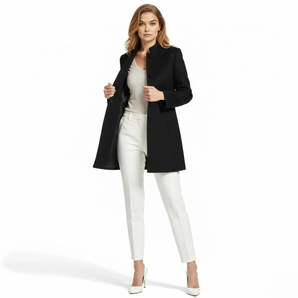 Model wearing the black Brandi funnel neck wool coat from Kouvr Fashion, styled with white trousers and heels, showcasing its structured, minimalist design.