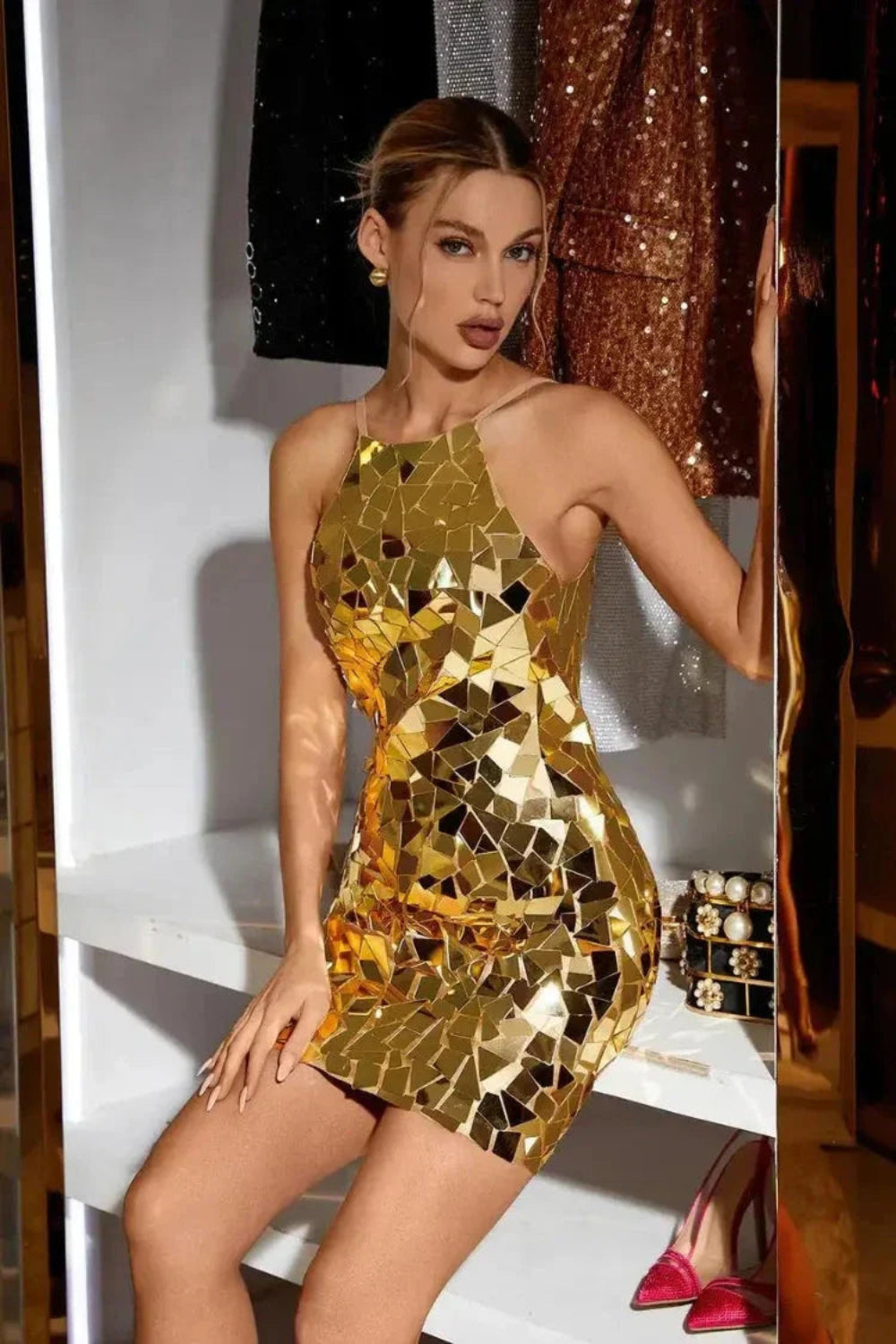 Model wearing Kouvr Brenda gold mirror mosaic halter neck mini dress in a luxury setting